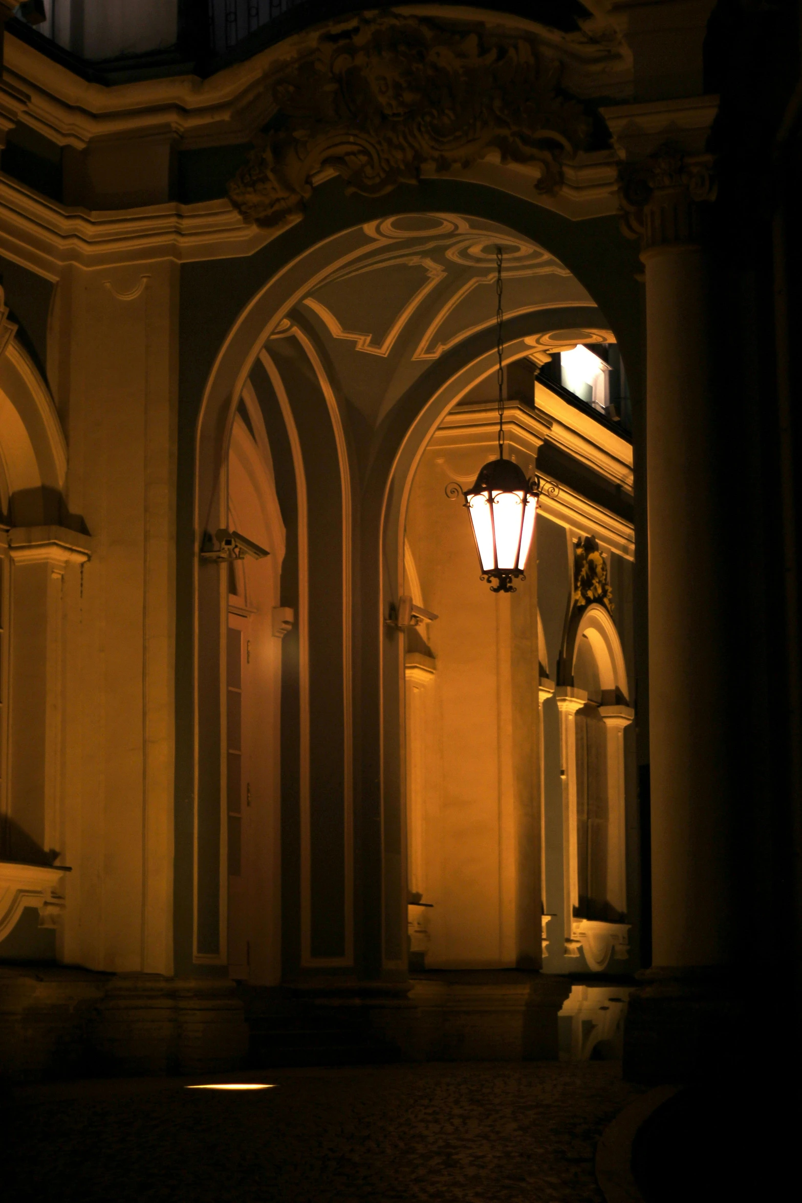 an arch with a lamp hanging over it at night