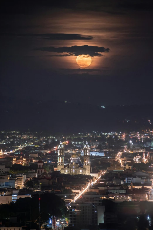 a full moon setting over a city at night