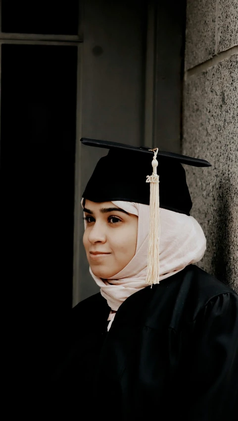 a woman in graduation clothes, wearing a black hat and scarf with a tassel