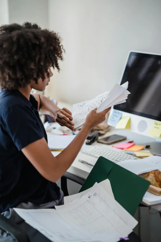 a woman reading papers at a computer desk