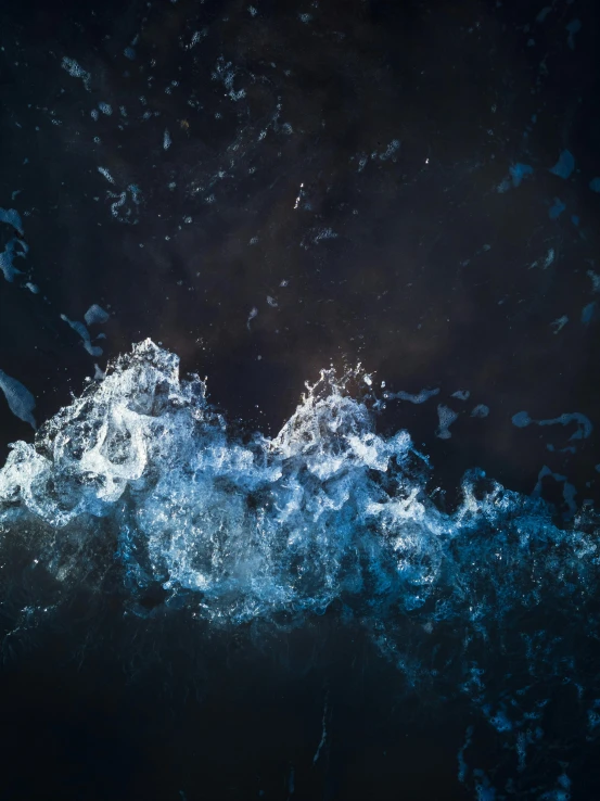 a bird flying over a ocean with blue water