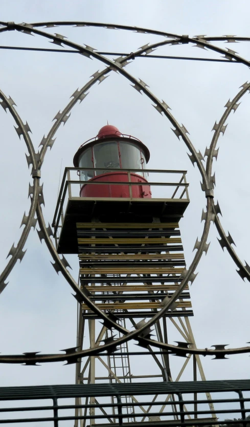 a light house behind a barbed wire fence