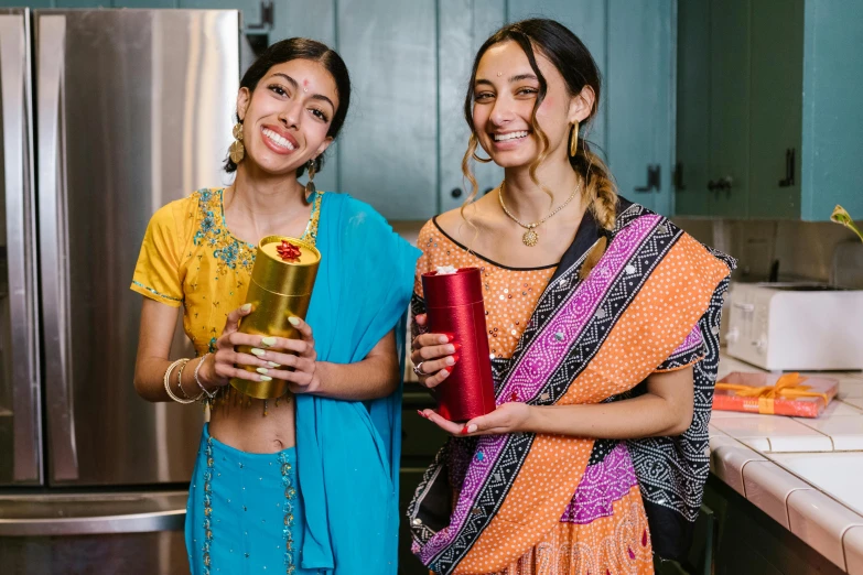 two women holding glasses are standing in the kitchen