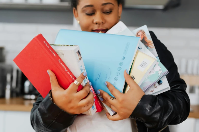 a girl in black jacket holding various colored files and a book