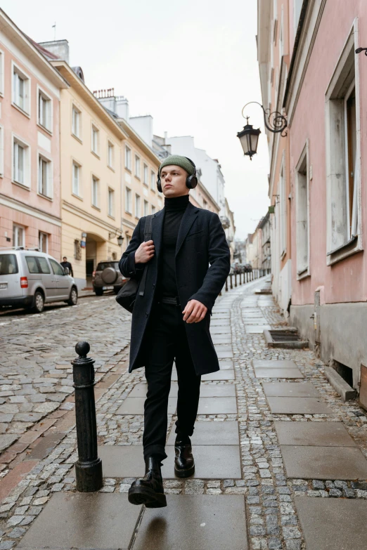 a man standing on the sidewalk in front of several pink buildings