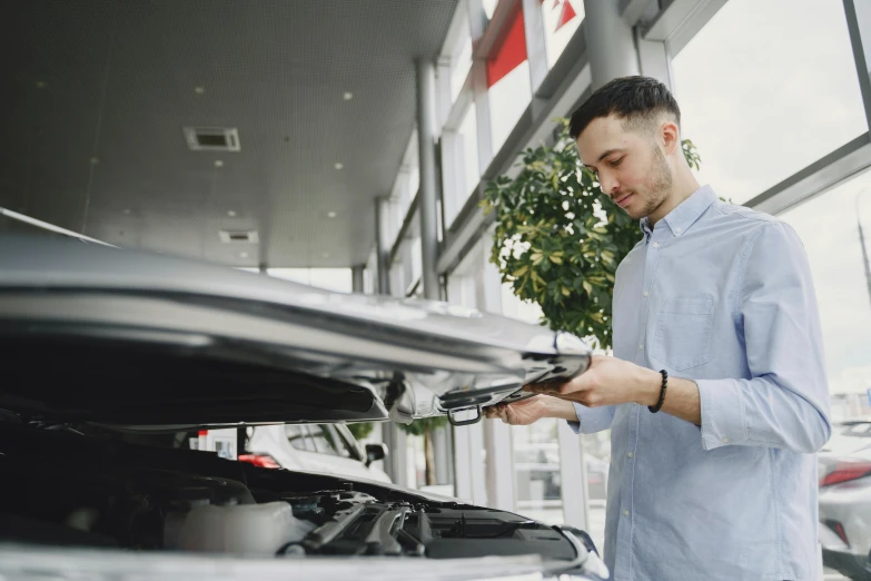 man checking car engine in the garage of dealership