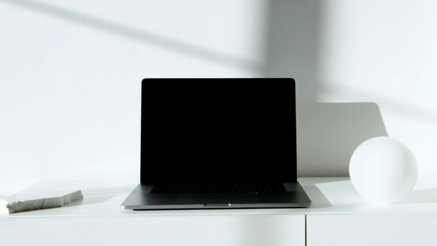 a small black laptop sits on top of a white dresser