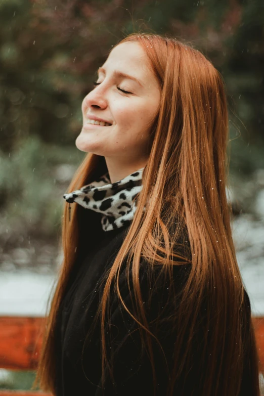 a woman smiling in the snow near some trees