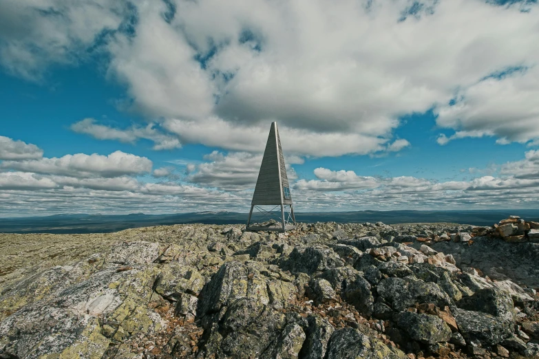 a person standing on top of a mountain with some rocks and grass