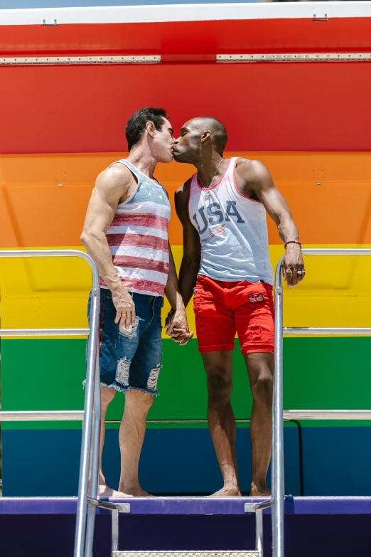 two people standing next to each other in front of a rainbow wall