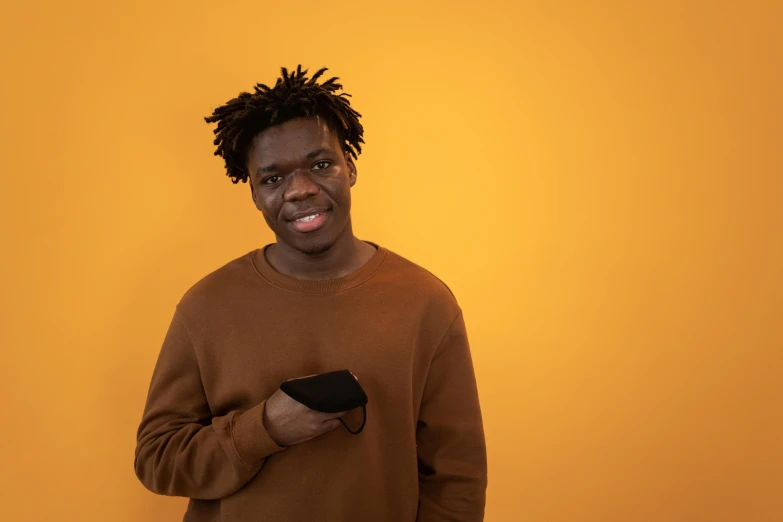 a man with his eyes half open wearing a brown sweatshirt holding a black remote control in his right hand