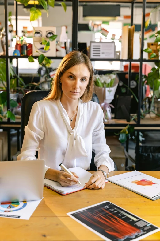 a woman sitting at a desk writing on a notebook