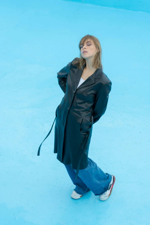 a woman is standing wearing a coat and jeans