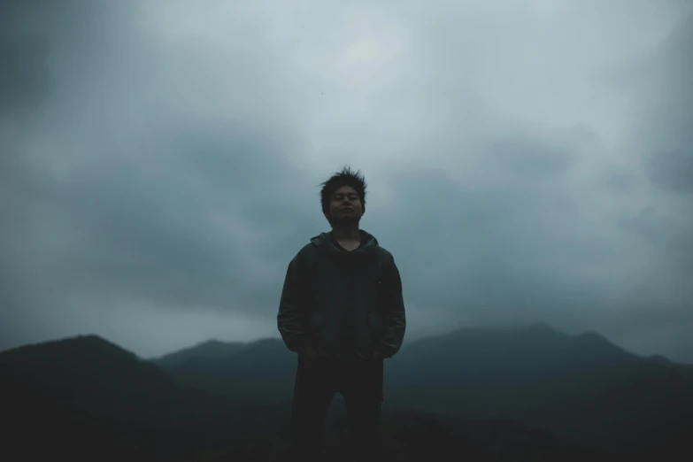 a person stands under a cloudy sky