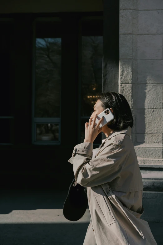 the woman in beige jacket is using her cell phone