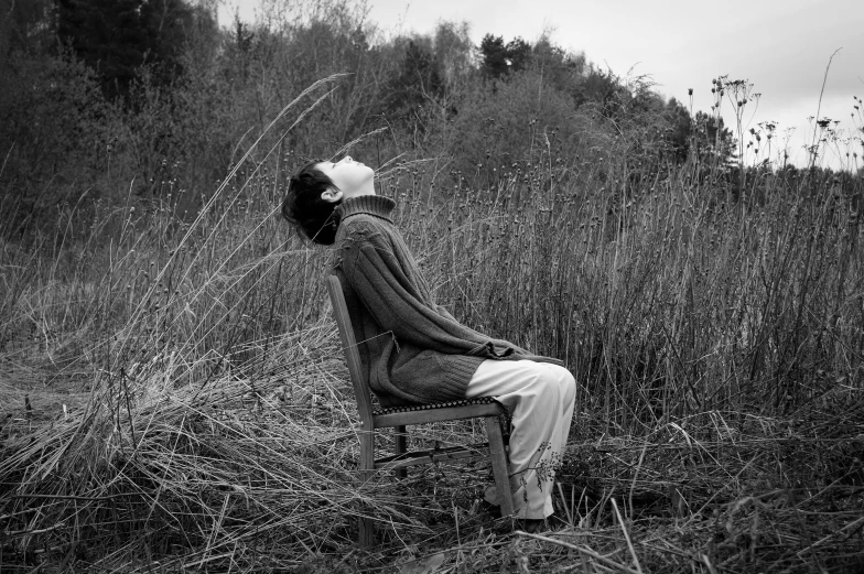 a woman sits in a chair looking up at the sky