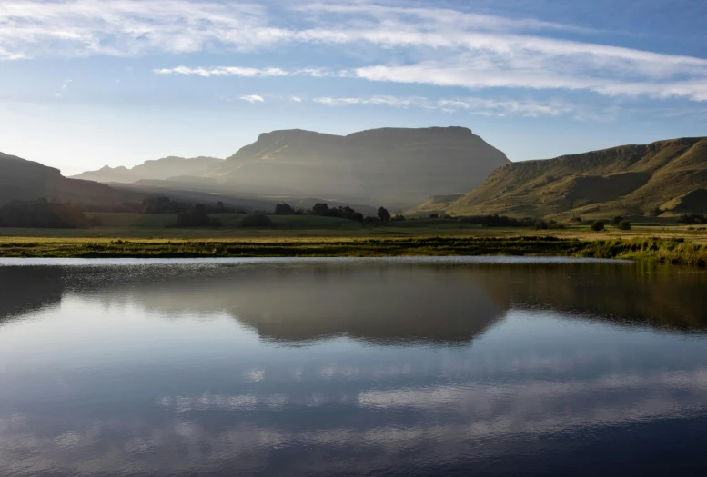 a body of water surrounded by mountains and grass