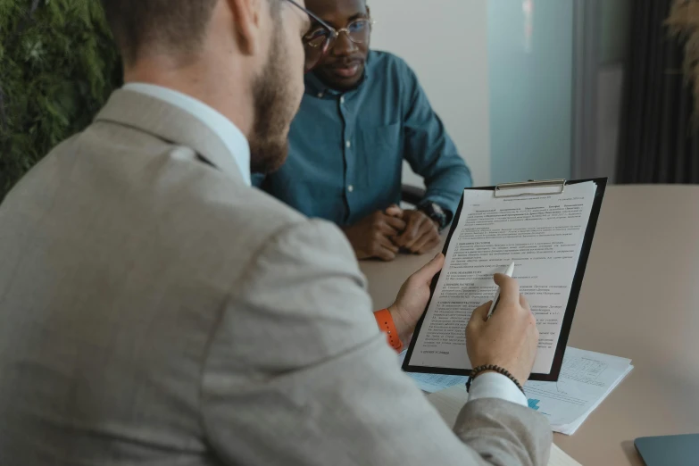 two business men sit at a desk and examine documents