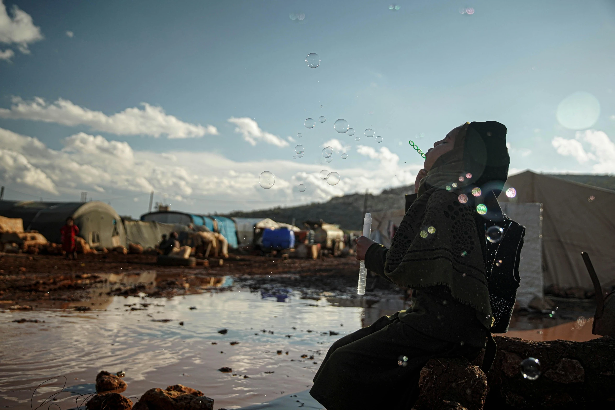 a woman is sitting in front of her tent with bubbles flying out of it