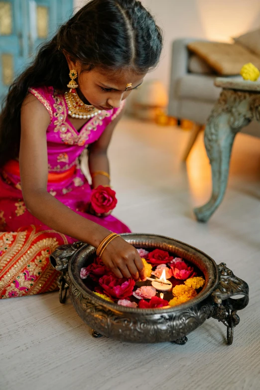 the girl is sitting in front of a pot full of flowers