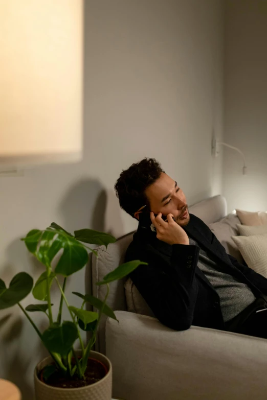 a man sitting on top of a couch next to a potted plant