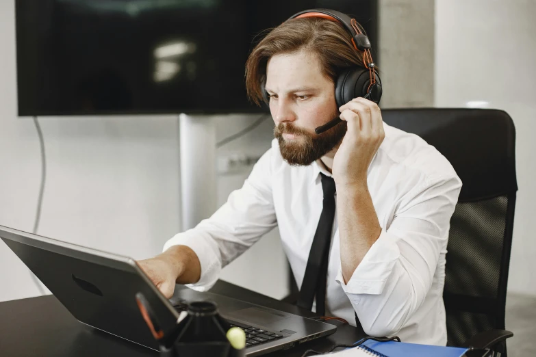 a man wearing headphones sitting in front of his laptop