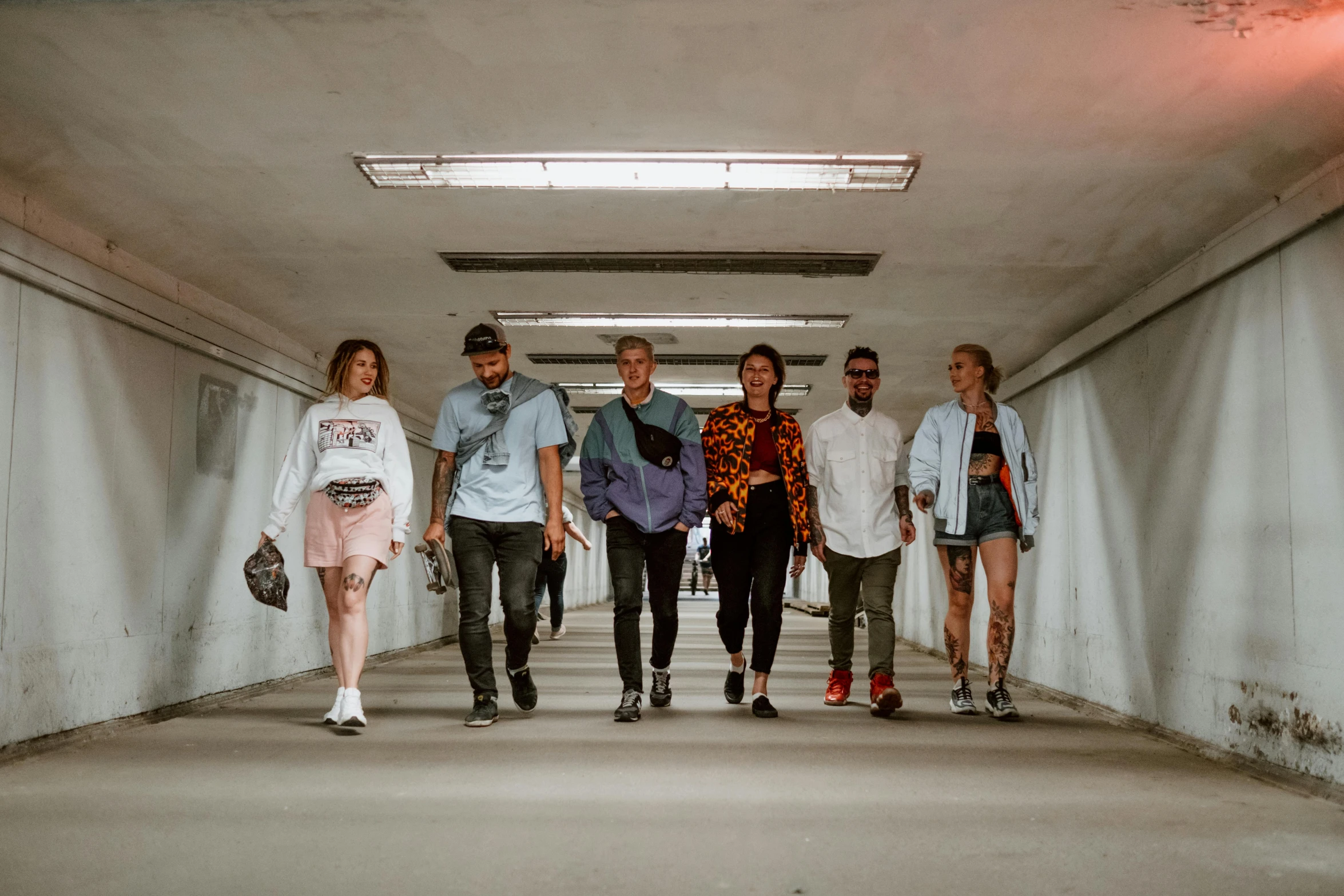 several people walking on a walkway with white walls