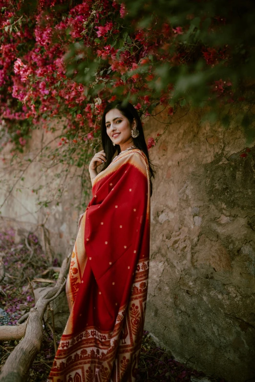 a woman wearing a red and gold sari under the bougaries