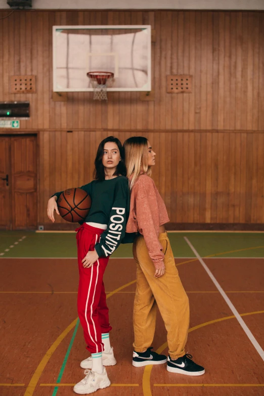 two young women are playing basketball in an indoor court