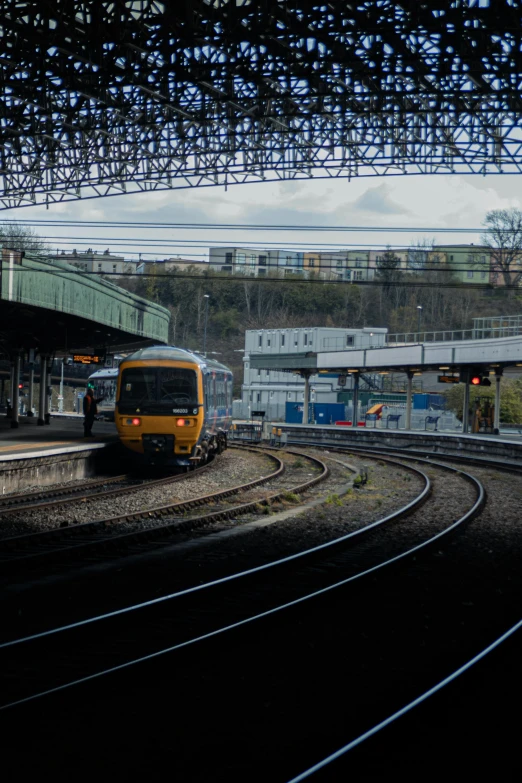 yellow train on the track underneath a bridge