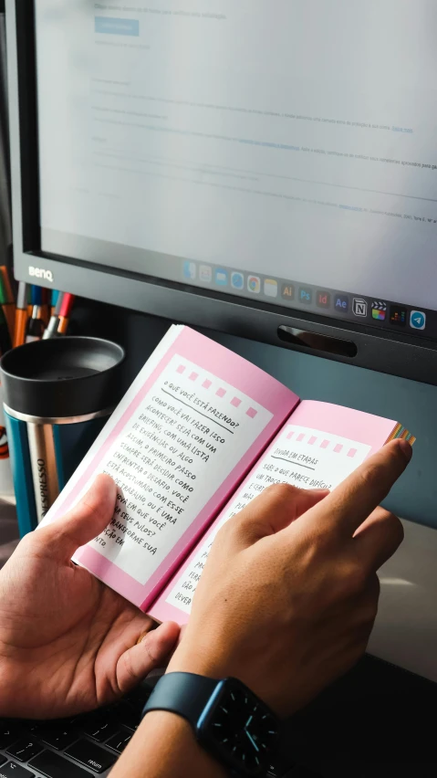 person writing on a notebook while looking at the screen