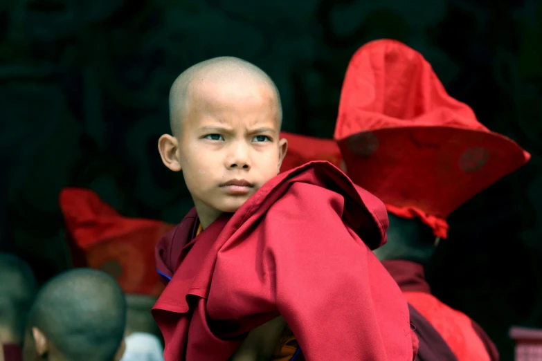 a small boy dressed as buddha sits next to other monk