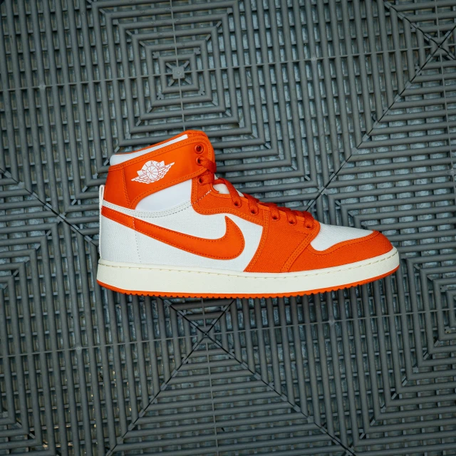 an orange and white basketball shoe on a gray grate