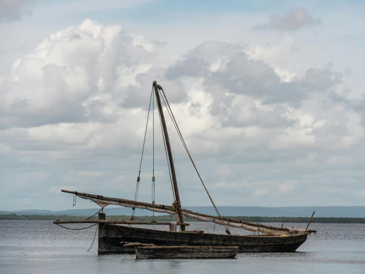 an old wooden boat sitting out in the middle of a bay