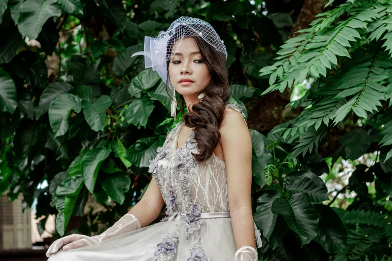 a woman wearing a dress and hat and sitting on a bench