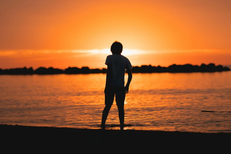 a person standing in the water watching a sunset