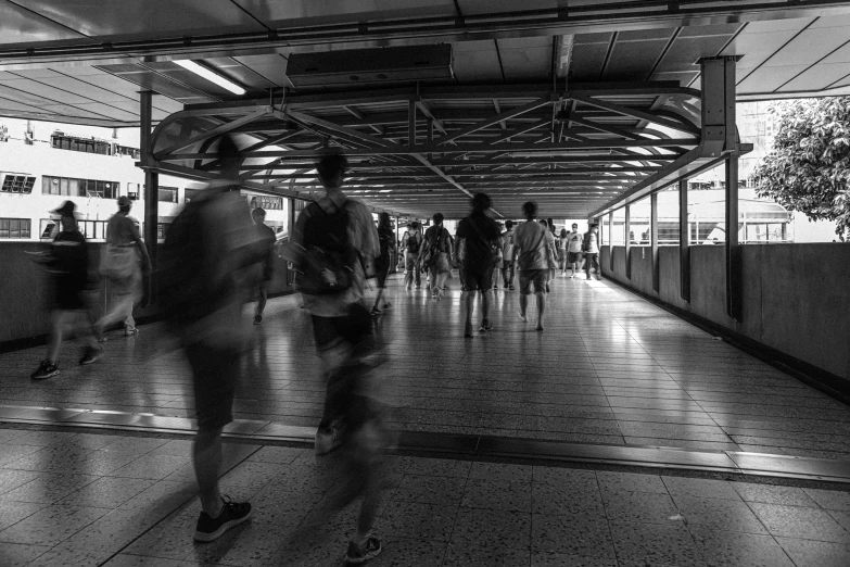 people walking down a walkway under a structure