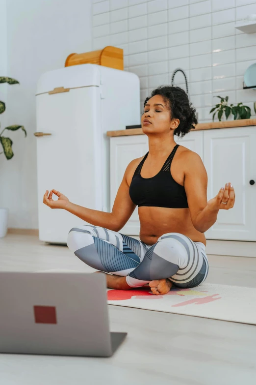 a woman sitting on the floor, holding up her hands while looking at her laptop