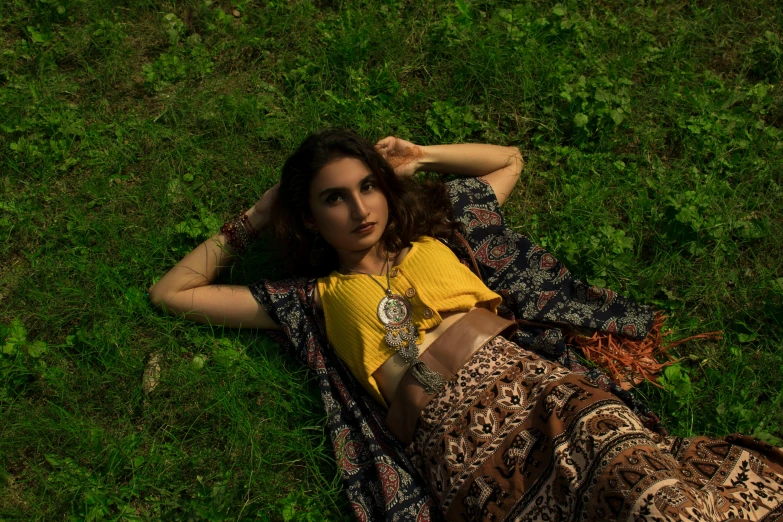 a woman is laying in the grass with her hands behind her back