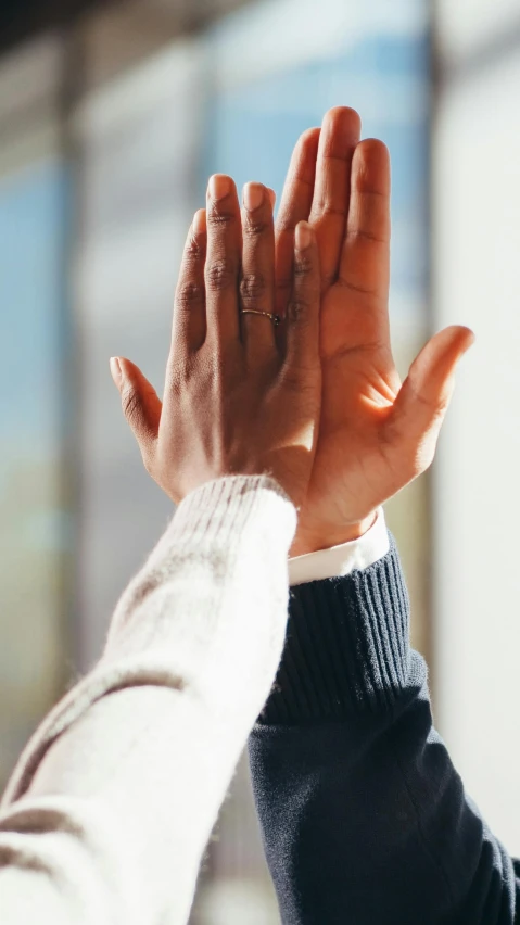 two people holding their hands up in the air