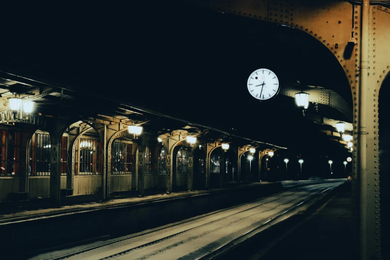 a clock is seen on the wall above the train tracks