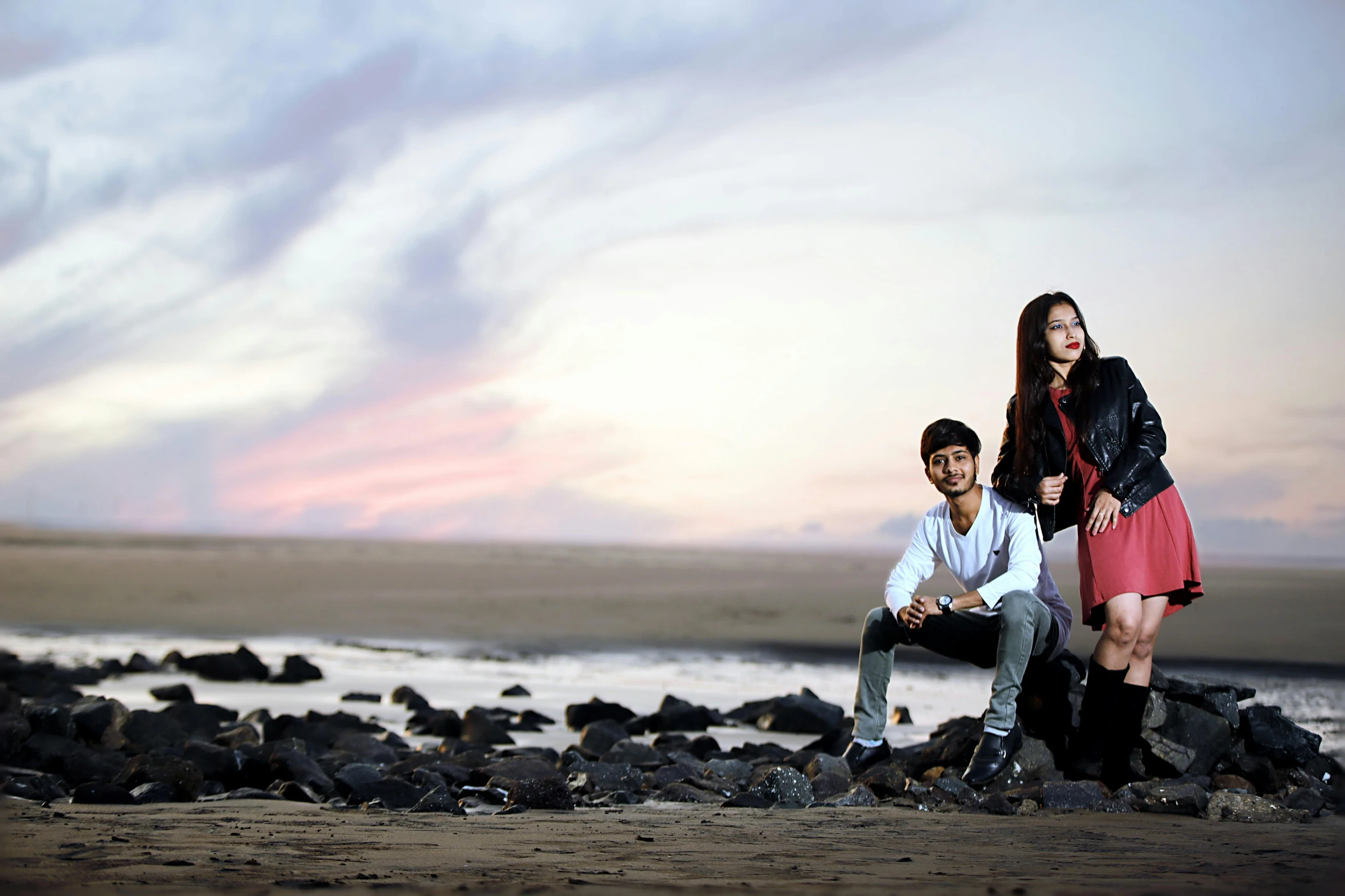 a man and a woman are sitting on a rocky shore