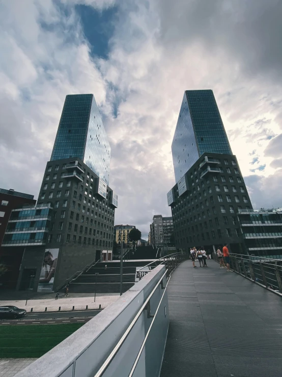 two high rise buildings surrounded by buildings under a cloudy sky