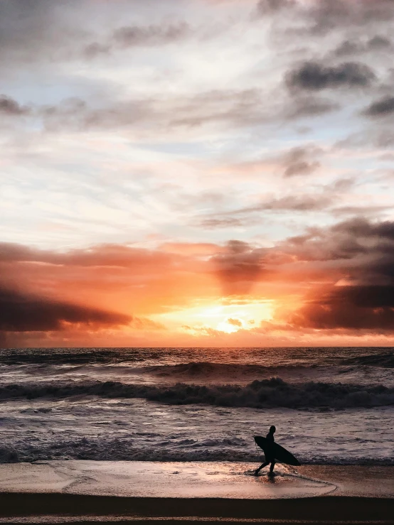 the sunset is setting and surfers are silhouetted against the ocean