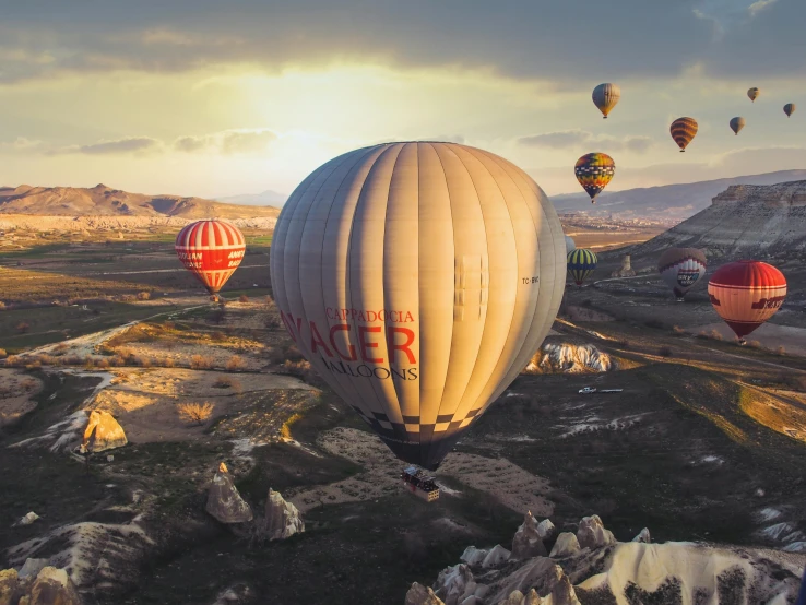 many large balloons are flying over a rocky terrain