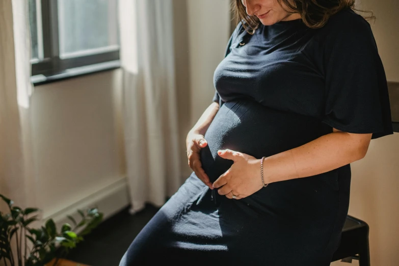 an pregnant woman sitting in the corner with her belly curled down