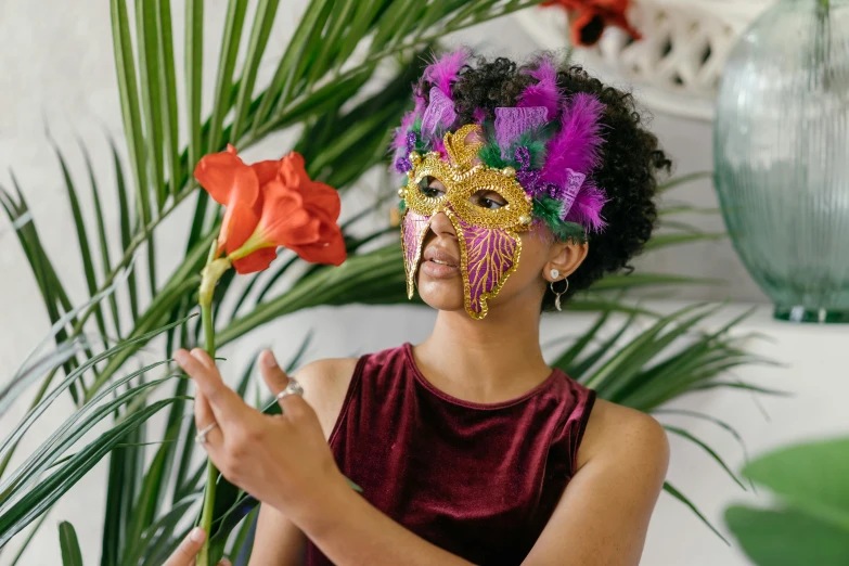 a girl in a mask holds up a flower