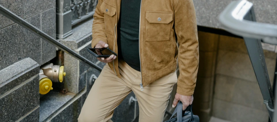 a man holding a phone and wearing beige pants