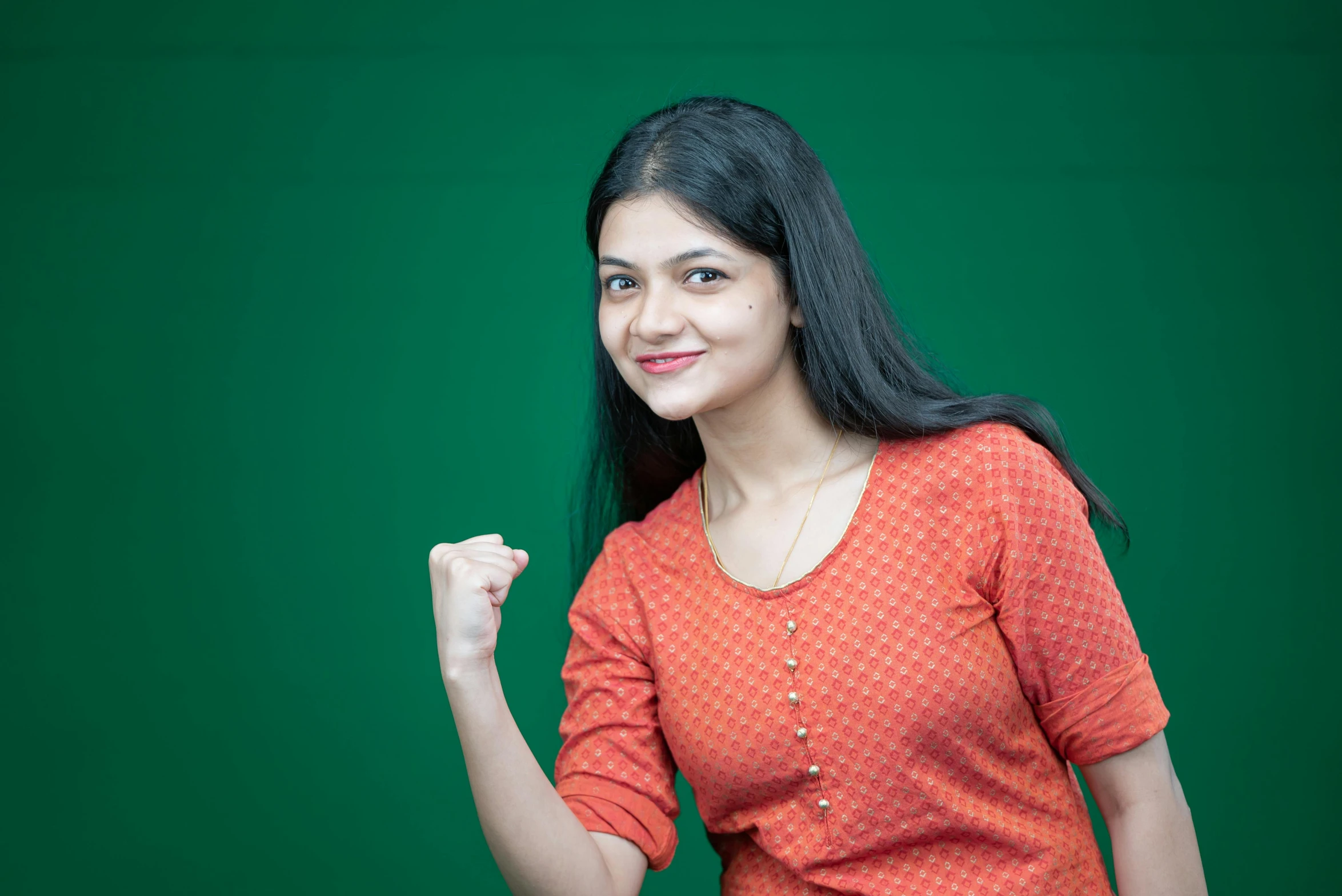 a smiling woman in orange shirt and jeans