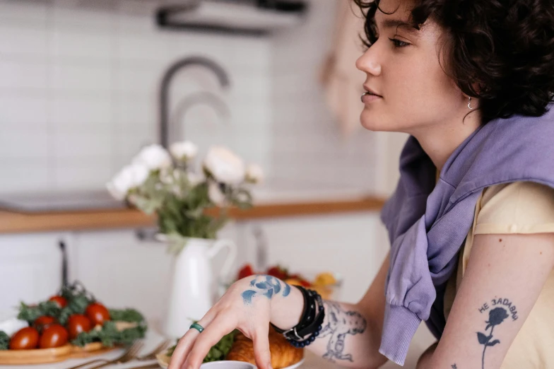 a woman with tattoos sits at a table with a plate